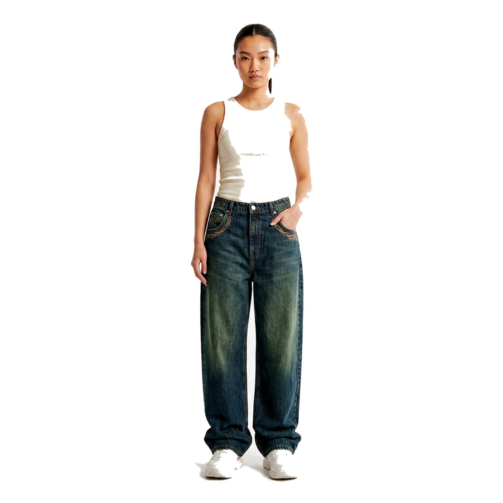 Woman styling embroidered baggy Y2K jeans in a medium wash, wide-leg fit