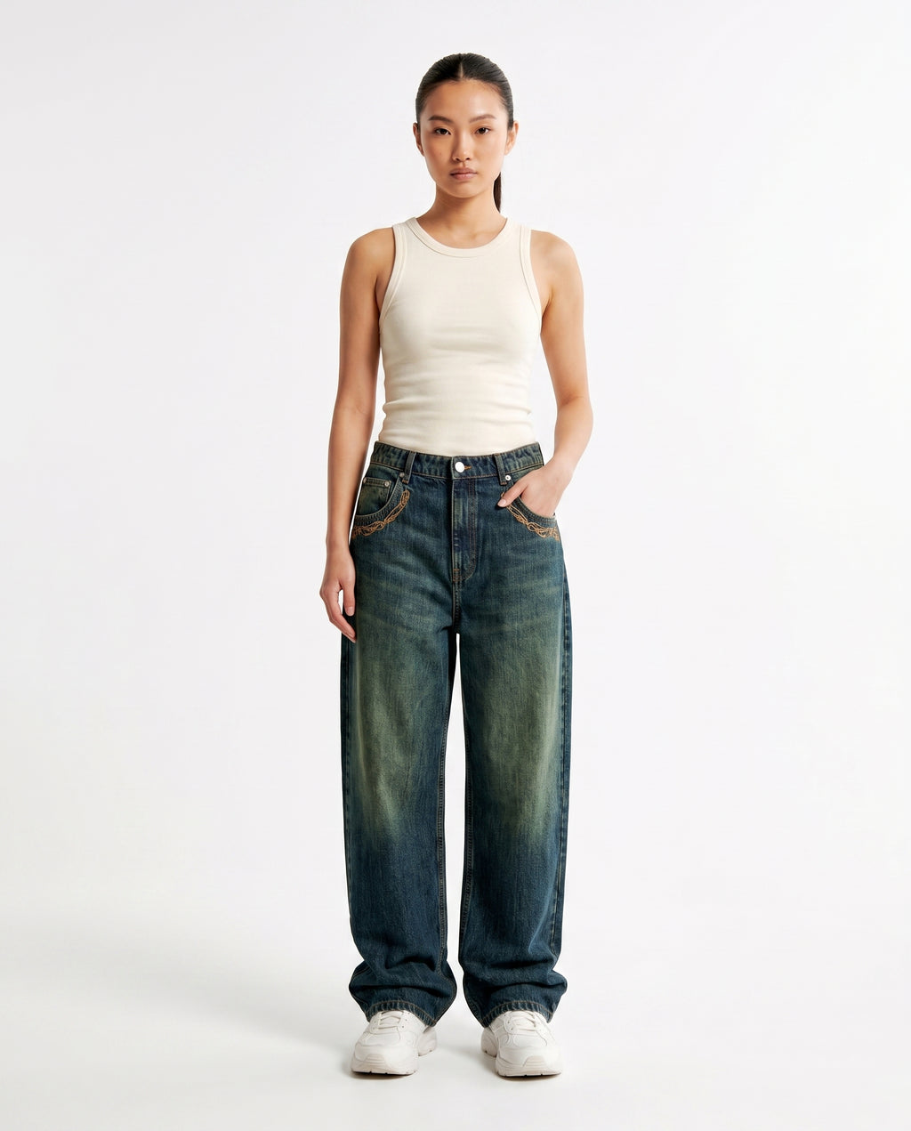 Woman styling embroidered baggy Y2K jeans in a medium wash, wide-leg fit